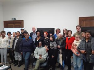 Photo taken at the London Mental Health Day event for voluntary and community organisations in Lambeth. A group of people from the event sitting and standing facing the camera and smiling.