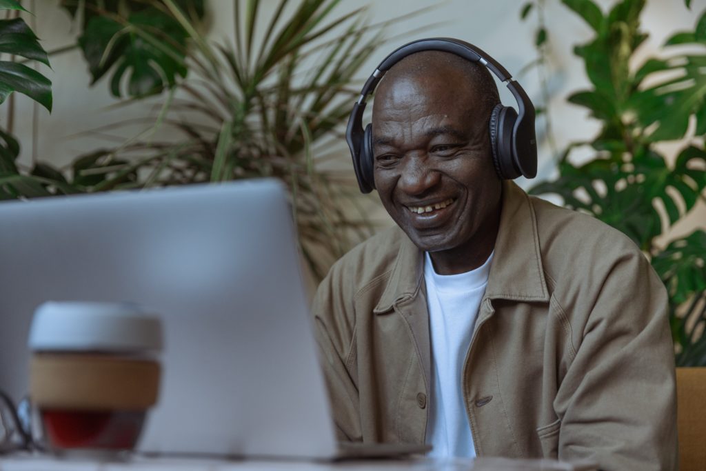 Man with headphones on laptop laughing