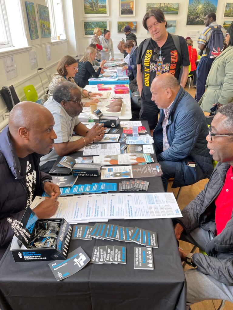 visitors to cancer awareness raising event sit at table and talk to stall holders