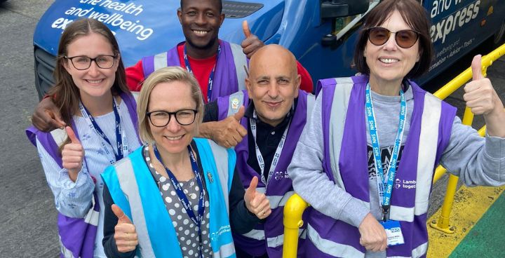 Lambeth Health Champions standing in front of Lambeth Health and Wellbeing bus, smiling with thumbs up