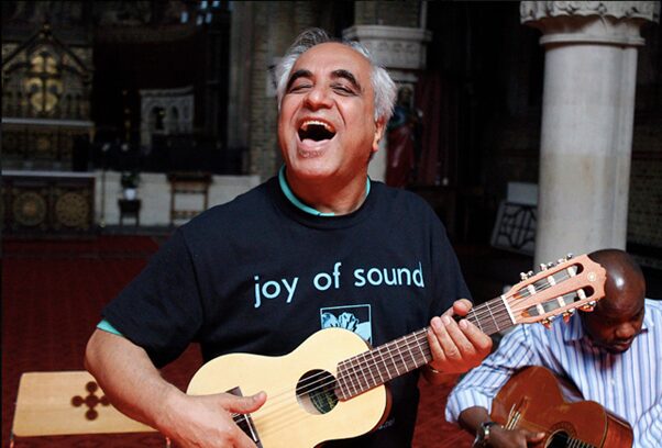 A man mid-chorus playing a ukulele taken from the Joy of Sound project